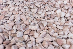 Many small polished  decorative stones used in landscape design with pink color tint
